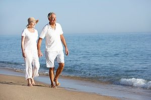 a couple walking on the beach enjoying their retirement and not worrying about their financial situaltion since they both have 401(k) retirement plans