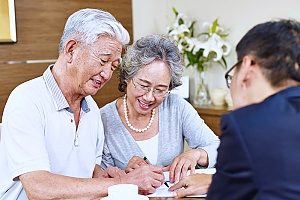 a retirement plans consultant assisting a retired couple as they sign a document for their 401(k) retirement plans