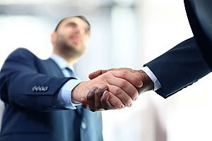 a business owner shaking hands and meeting with wealth management consultans to discuss how profit sharing plans will benefit him and his employees