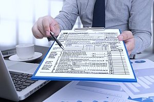 a man holding a tax form where a man will receive exemptions since he is funding his 529 college savings plan for his future son or daughter