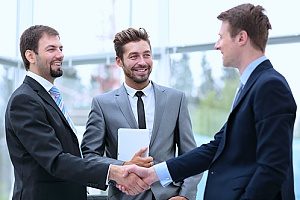 two businessmen shaking hands with each other as they meet with their financial consultant to meet about tax deferred fix annuities