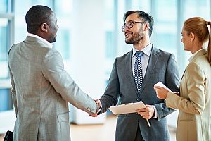 the owner of a financial consulting firm shaking hands with a small business owner in Fairfax, VA as they meet to talk about retirement plans for his employees